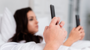 Casal usando os celulares na cama, sem entender qual é o problema da pornografia