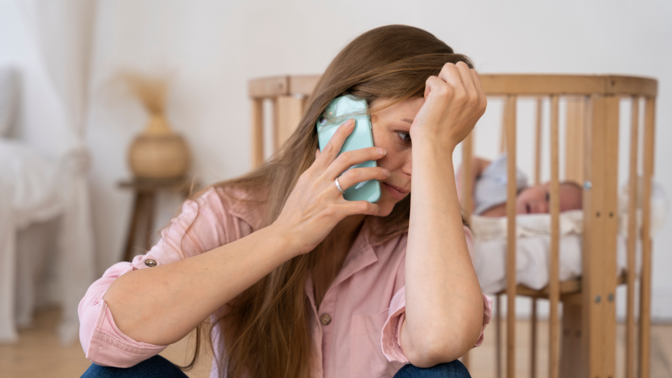Mulher ao lado do berço telefonando para pedir ajuda, pois ser mãe cansa