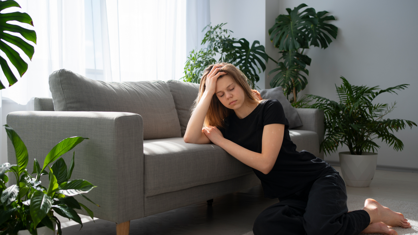 Mãe esgotada no sofá, pensando em como aliviar a tensão mental na maternidade