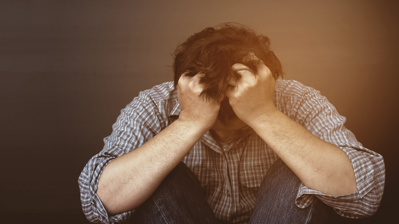 Homem sentado no chão, puxando os cabelos, para falar sobre Viktor Frankl e o sofrimento